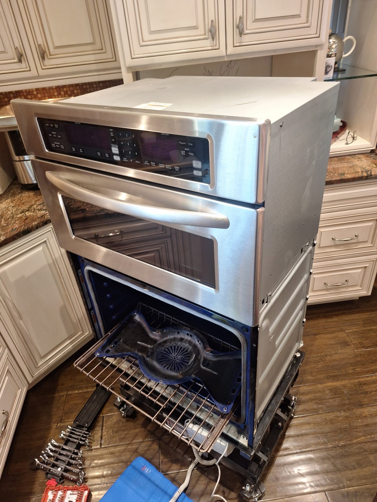 Double wall oven on a service lift with lower door removed and convection fan cover exposed