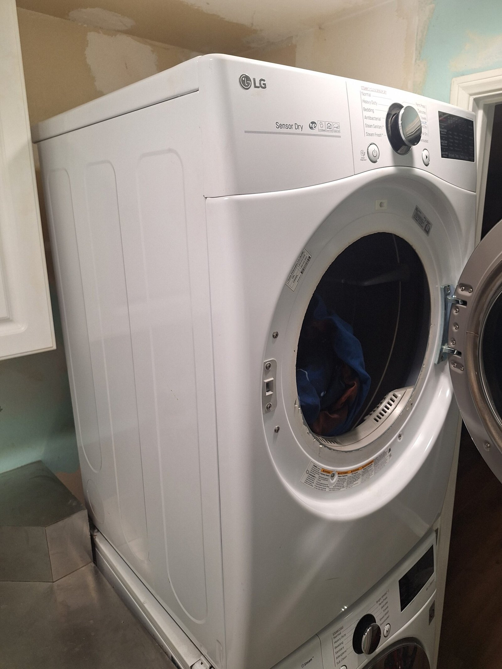 White LG Sensor Dry dryer stacked above a washer with the dryer door open