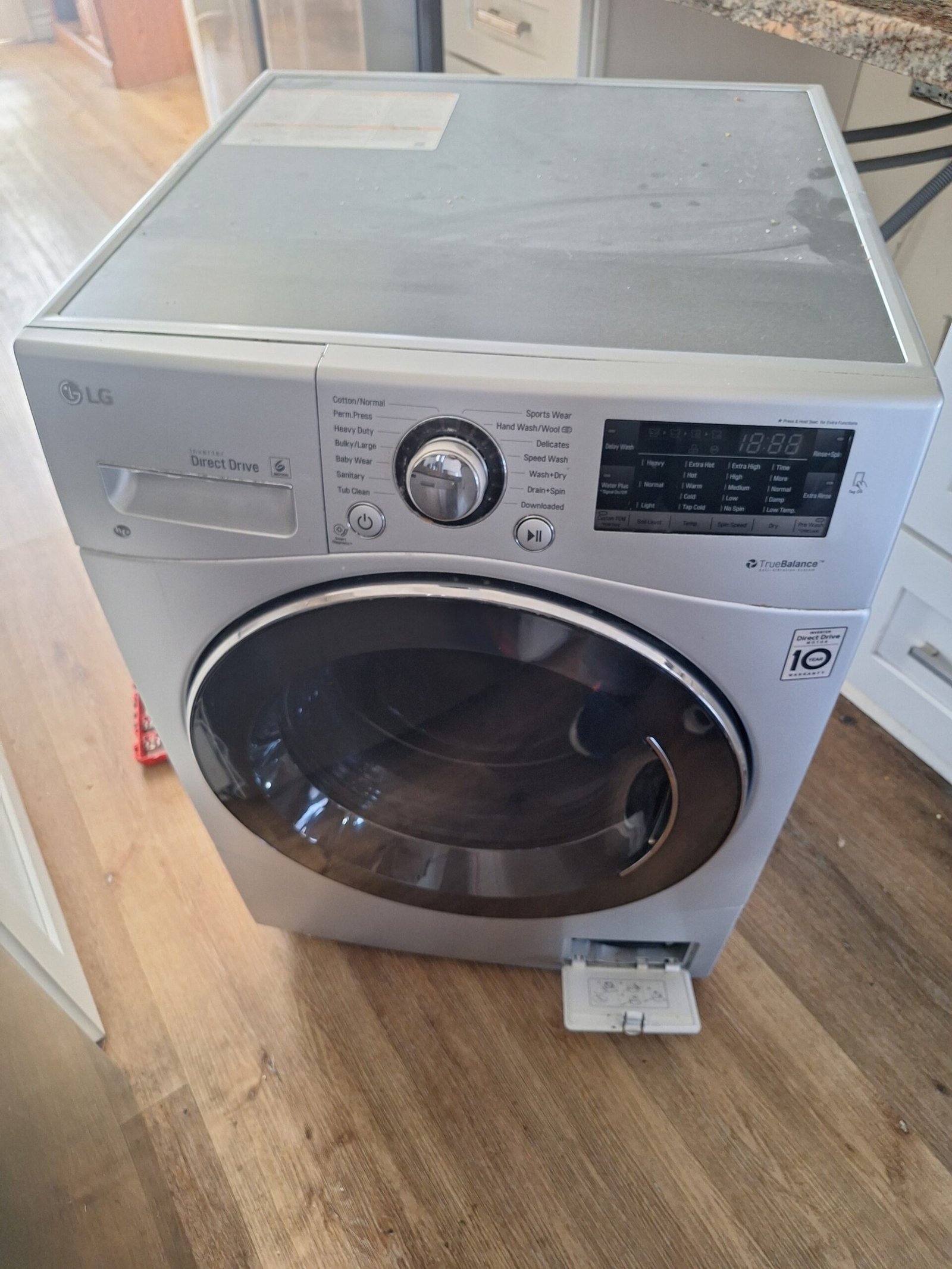 LG front-load washer pulled forward with the lower drain-filter service hatch open